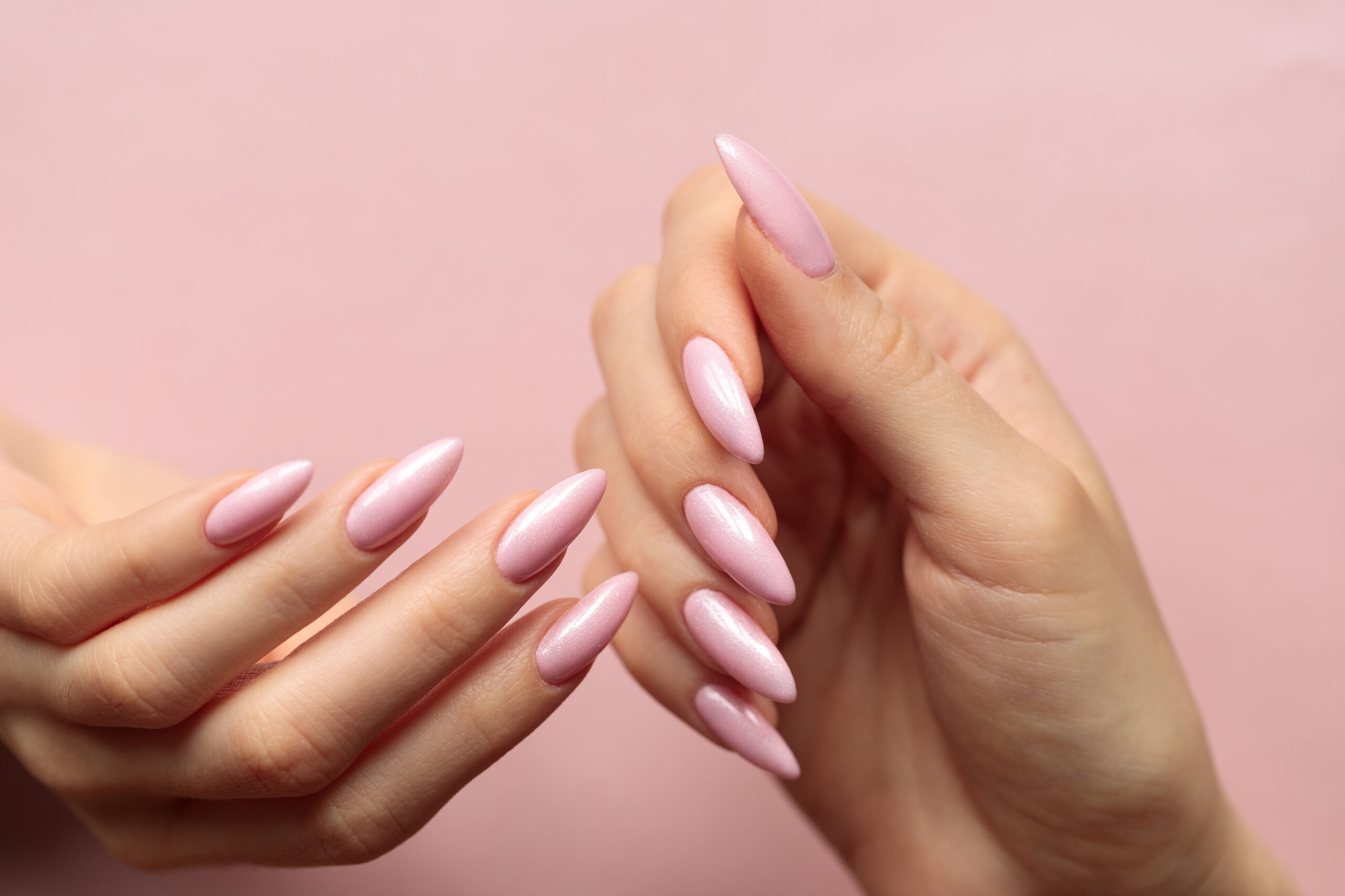 Girl's hands with a beautiful pink manicure on a light pink back